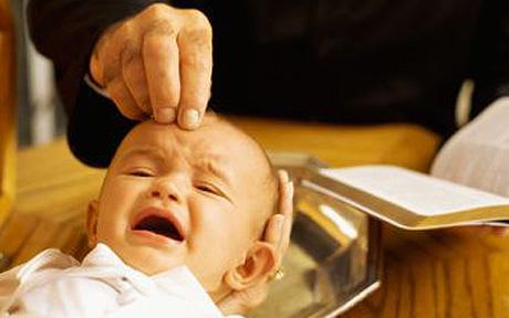 mid section view of a priest baptizing a baby boy